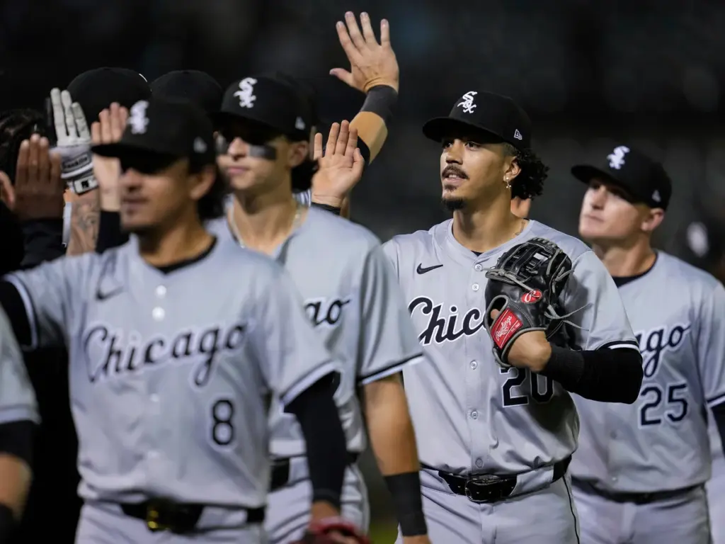 Chicago White Sox baseball players in gray uniforms high-five each other on the field after a game.
