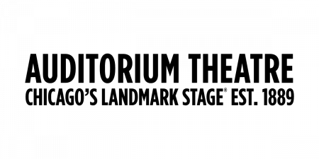 A black cat sits with its tail curled around its body, looking forward with alert, upright ears and wide eyes.