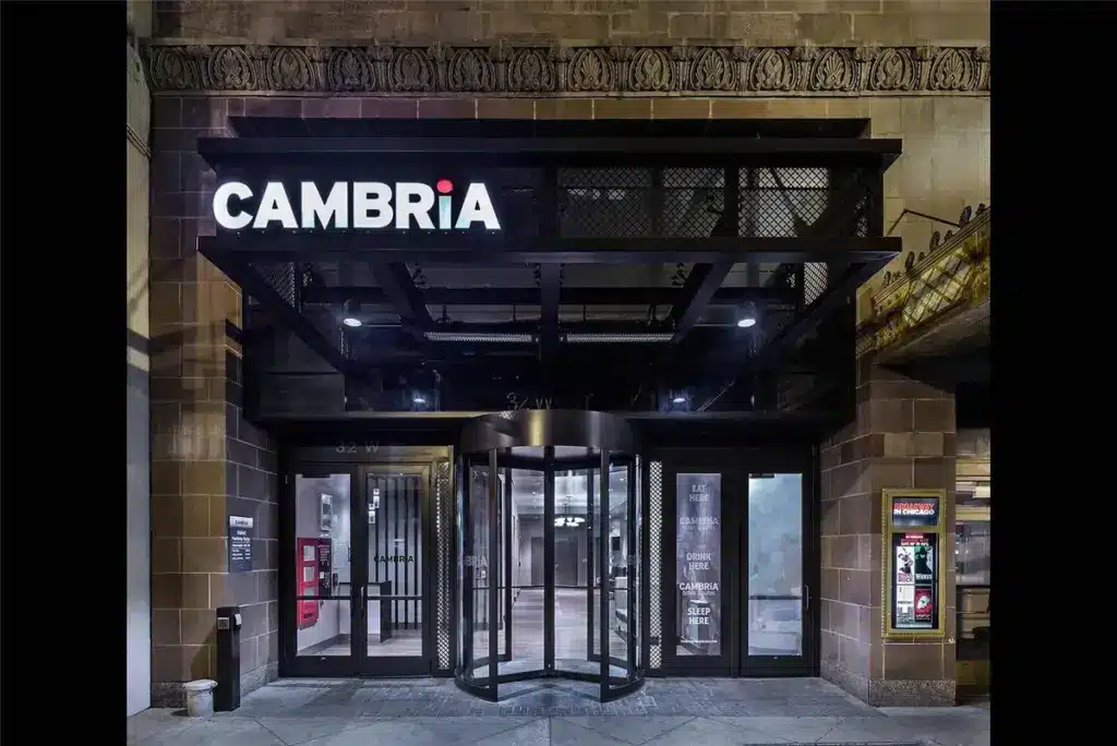 Exterior view of a building entrance with a revolving door and a large illuminated sign reading "CAMBRiA" above the door.