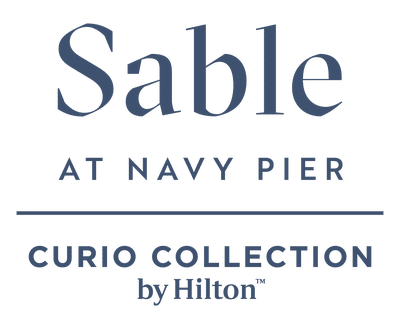 Logo for Sable at Navy Pier, part of the Curio Collection by Hilton, featuring text in blue capital and lowercase letters on a light background.